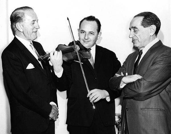 three men in suits, one playing the violin